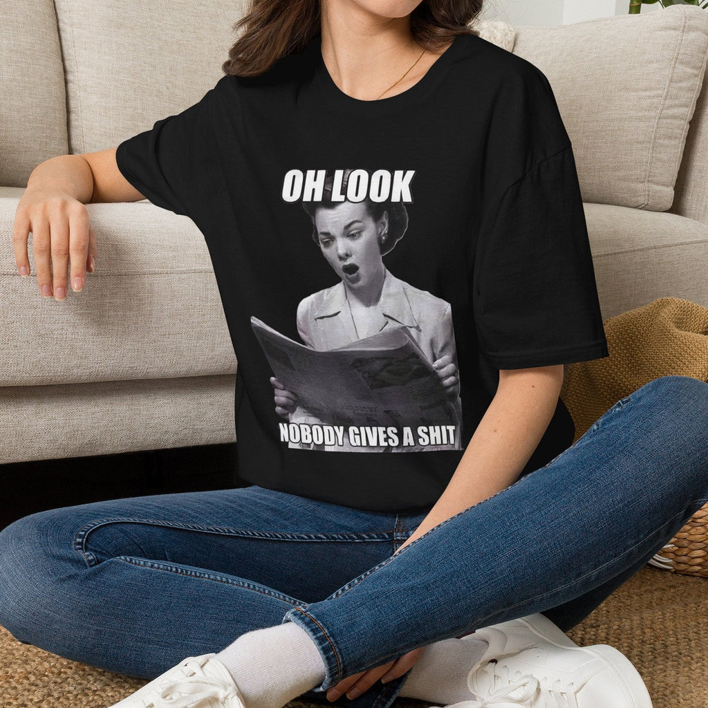 Sarcastic retro graphic t-shirt featuring a vintage woman looking at a newspaper reading Oh Look Nobody Gives A Shit.