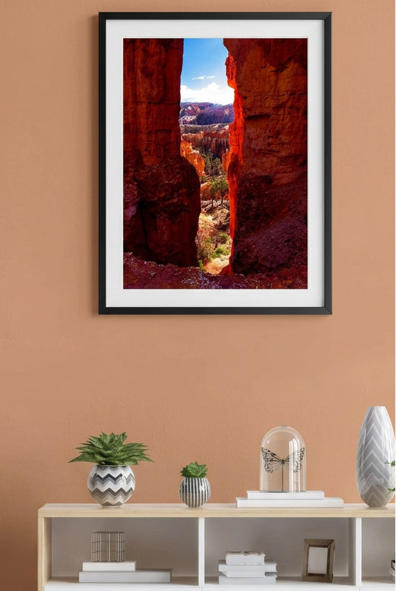 Fine art photograph looking through a narrow orange hoodoo gap at Bryce Canyon National Park toward a sunlit canyon vista.