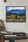 Fine art photography print of a misty morning over the Colorado Rocky Mountains with a sunlit alpine meadow and a distant valley lake.