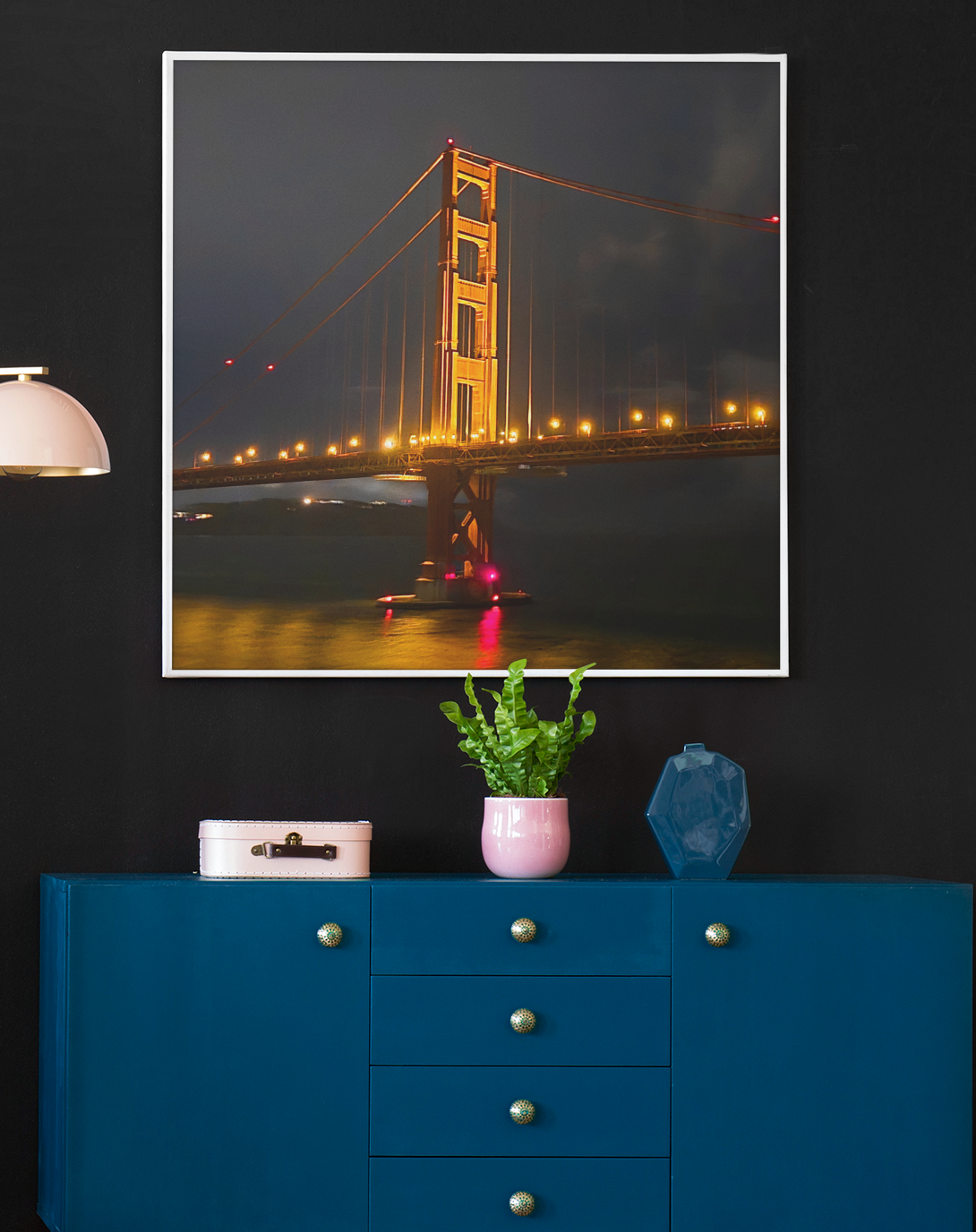 Night photography of the Golden Gate Bridge illuminated in gold against a dark clouded sky, casting glowing reflections on the water below.